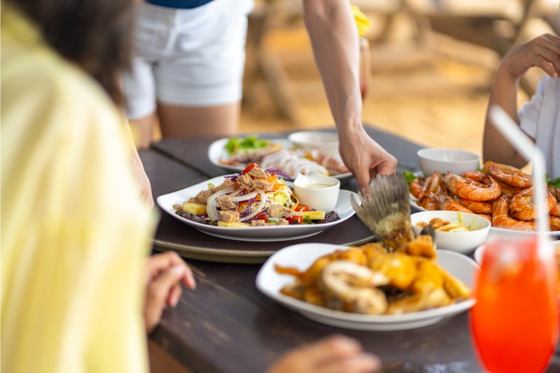 Asian couple and little kids having lunch together at beach restaurant